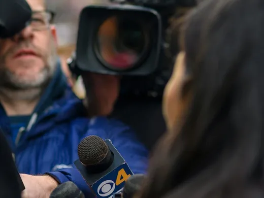 Micros de plusieurs chaînes de télévision et caméra tendus vers une personne interviewée